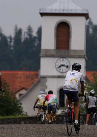 Photo de plusieurs cyclistes sur leur vélo avec une église floutée en fond